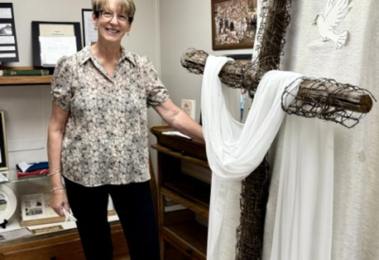 Director Neva Jordan poses in front of cross as part of new church exhibit. 