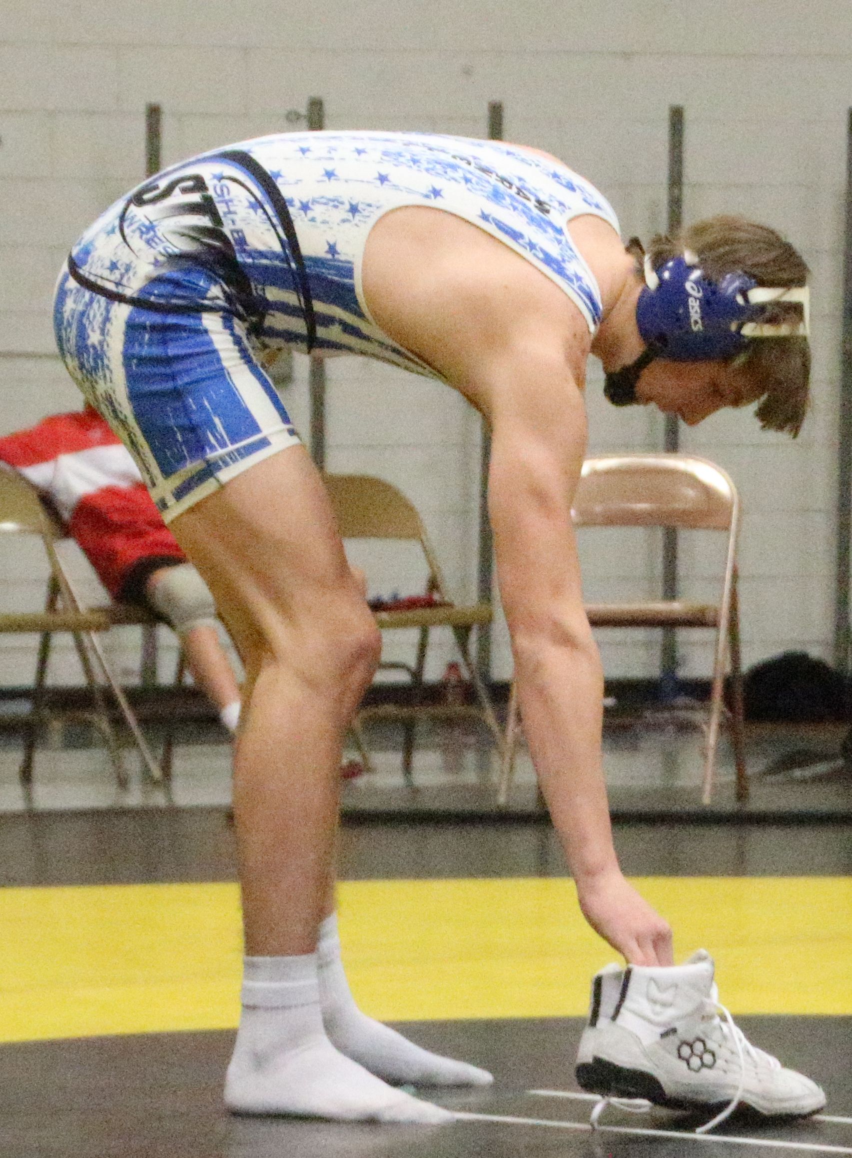 South Hardin-BCLUW senior Logan Aicher leaves his shoes at the center of the mat to symbolize the end of his high school wrestling career after injuries sustained in a car accident in the summer of 2021. (Jake Ryder photo)